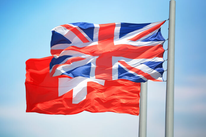 British,And,Swiss,Flags,Amid,Blue,Skies
